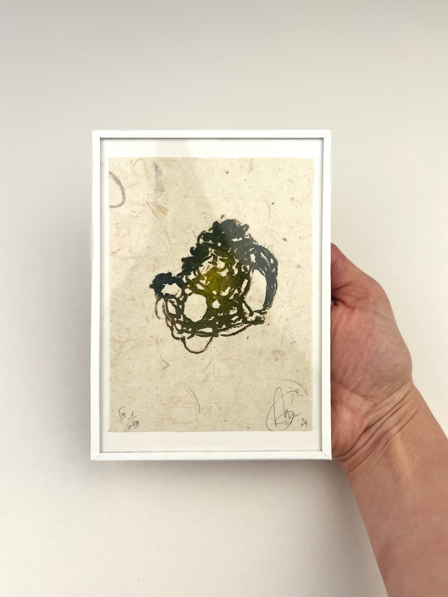 Estampe de crochet réalisée à la main, imprimée sur papier fibreux avec un motif organique en nuances d'encres vertes, présentée dans un cadre blanc