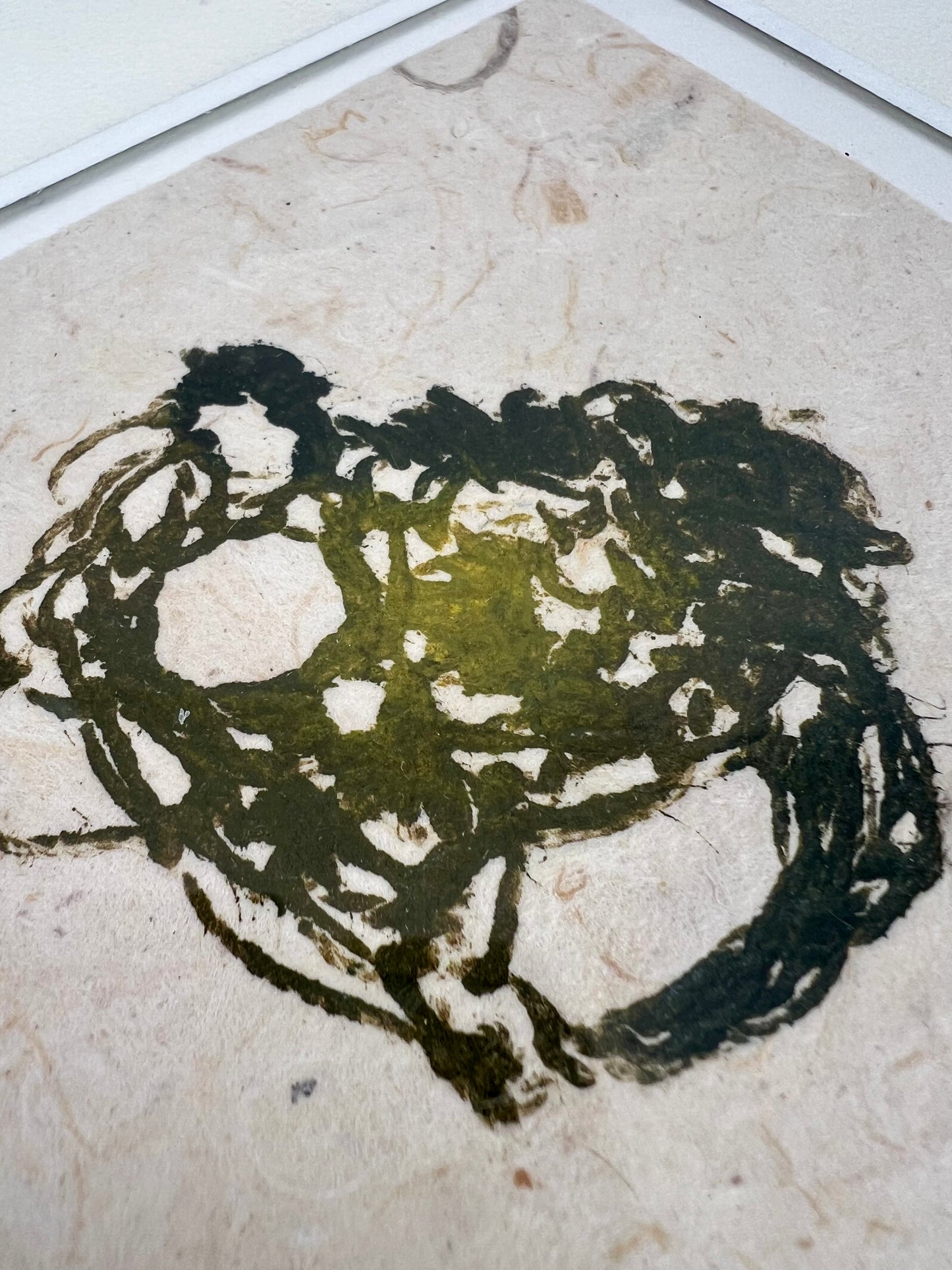 Détail de l'estampe de crochet verte encadrée sur papier texturé artisanal